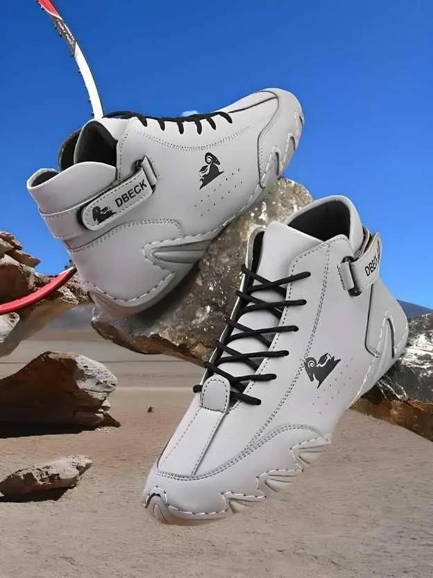 White sneakers with black laces on a rocky surface with a blue sky.